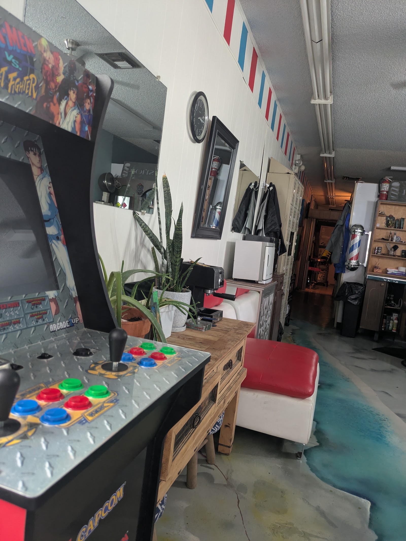 Interior view with X-Men vs Street Fighter arcade machine, waiting seating and hallway
