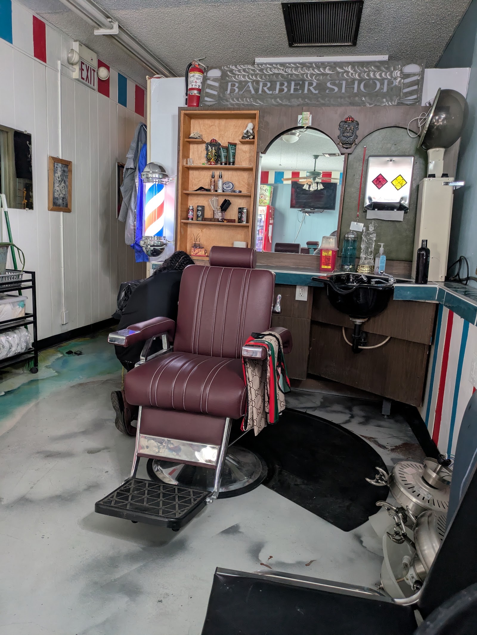Vintage barber chair under a 'Barber Shop' metal sign with mirror station and hood dryer